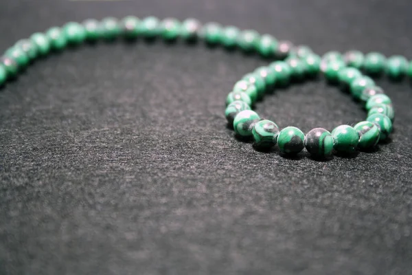 Siyah keçeli arka planda yeşil boncuklar. Metin için boşluk.