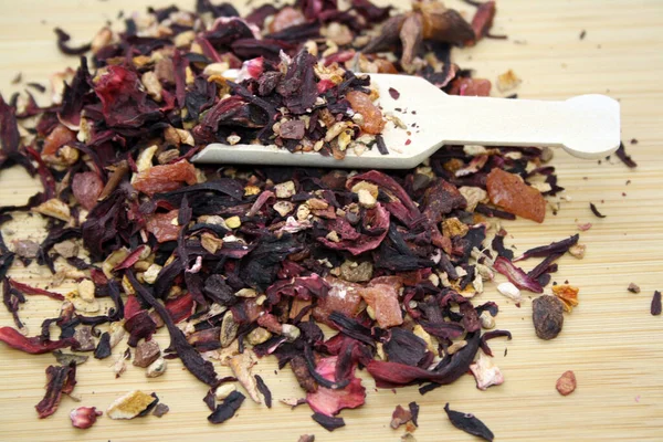 Fruit tea with the addition various herbs on wooden background.