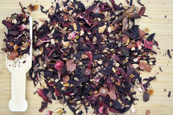 Fruit tea with the addition various herbs on wooden background.