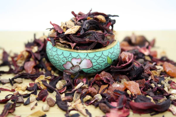 Fruit tea with the addition various herbs on wooden background.