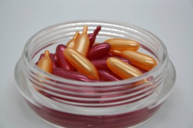 Yüzü için kozmetik yağlı bir kavanozda altın ve pembe kapsüller. Metin için arkaplan.