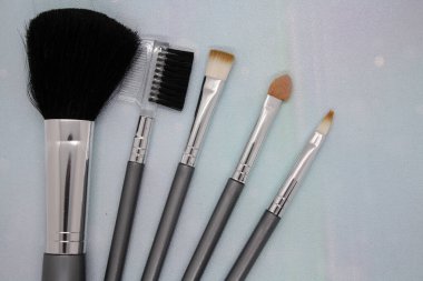 Açık mavi arka planda makyaj fırçaları. Metin için boşluk.