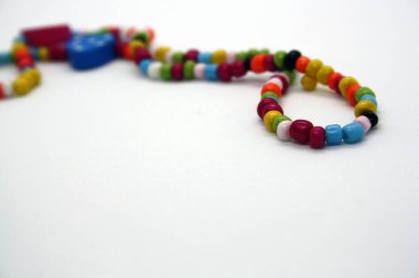 Beyaz arka planda boncuklardan yapılmış bir bilezik. Metin için boşluk.