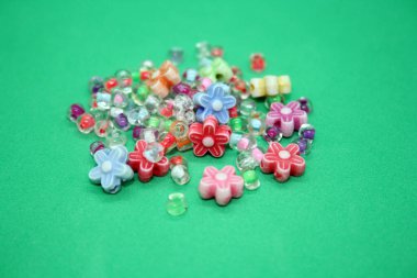 Yeşil arka planda bilezik yapmak için renkli boncuklar. Metin için boşluk.