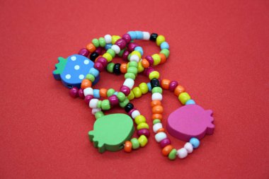 Kırmızı arka planda boncuklardan yapılmış bir bilezik. Metin için boşluk.