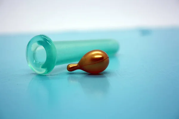 A jar for facial massage and gold capsules with oil. Blue background.