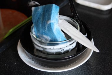 Sabunlu bulaşıklar lavaboda. Siyah tezgah.