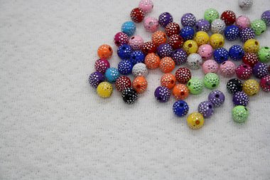 Beyaz tekstil arka planında renkli boncuklar. Metin için boşluk.