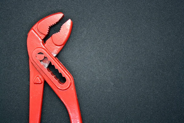 Red adjustable wrench. Tool for tightening nuts on a black background.