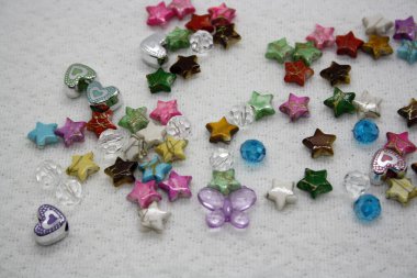 Beyaz tekstil arka planında renkli boncuklar. Metin için boşluk.