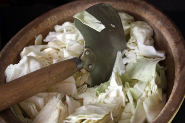 Ağaç sapıyla lahana doğramak için bir bıçak. Tahta bir kasede dilimlenmiş lahana. Mutfak arka planı.