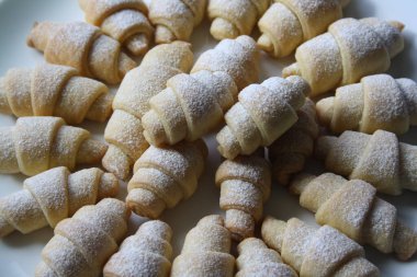 Taze pişmiş çörekler beyaz bir tabakta pudra şekeri serpiştirilmiş..