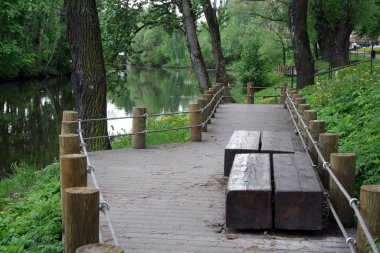 Parkın deniz kıyısındaki dinlenme yerinde. Göletin kıyısındaki ahşap banklar. Çevre dostu dinlenme.