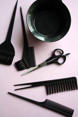 Bir kuaför için alet takımı. Siyah makas ve pembe arka planda bir tarak..