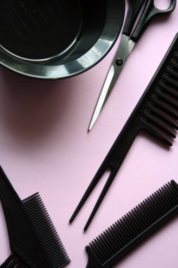 Bir kuaför için alet takımı. Siyah makas ve pembe arka planda bir tarak..