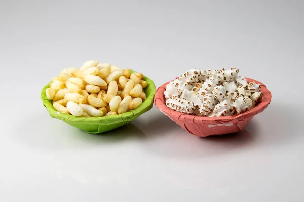 puffed rice and popped rice in green and pink paper bowl or thonga packet on white background studio shoot. local name in Bangladesh Muri and Khoi. traditional folk food among Bengal\'s.