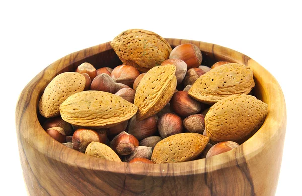 Amandes et noix dans un bol en bois fait à la main isolé sur fond blanc . — Photo