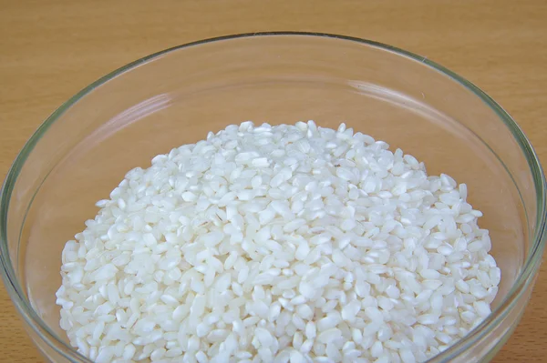Белый сухой сырой рис в миске на деревянном фоне . — стоковое фото