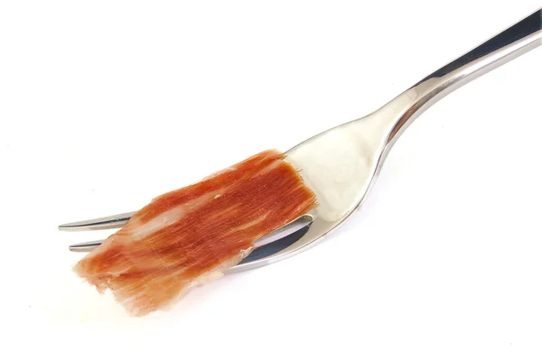 Serrano ham slice on metal fork. Jabugo. Spanish tapa. — Stock Photo, Image