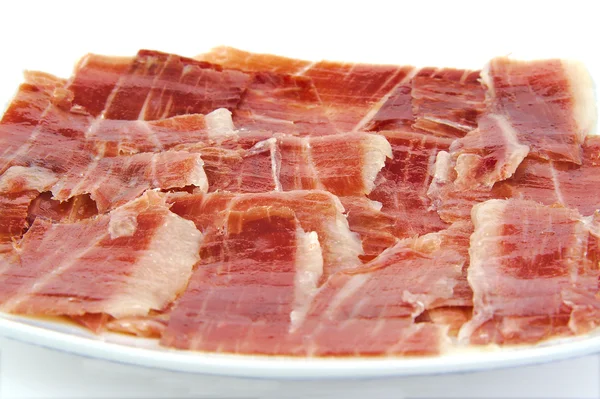 Closeup of serrano ham slices on a white dish. Jabugo. Spanish tapa. — Stock Photo, Image