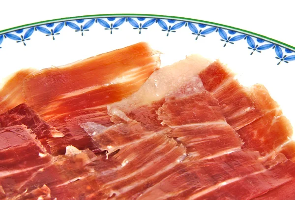 Närbild av serrano skinka segment på en vit maträtt. Jabugo. Spanska tapa. — Stockfoto