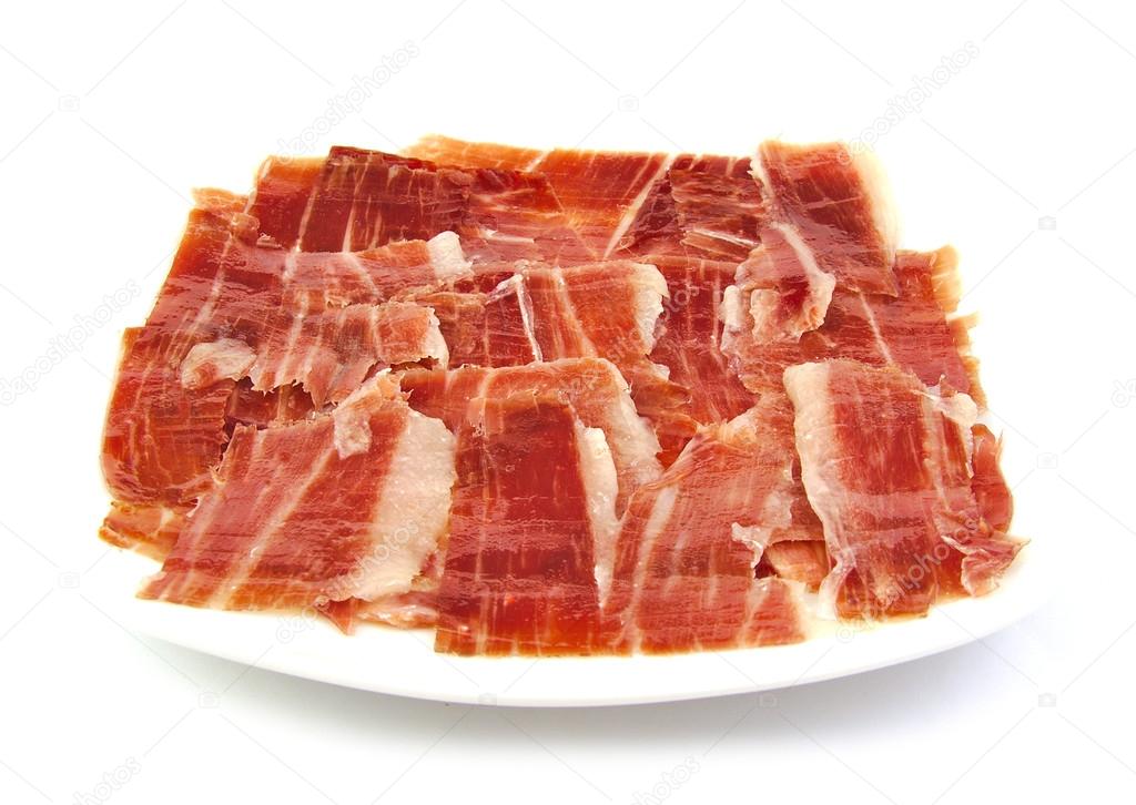 Serrano ham slices on a white dish. Jabugo. Spanish tapa.