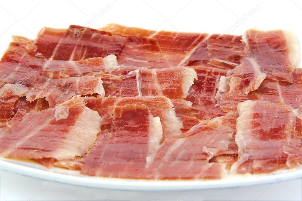 Closeup of serrano ham slices on a white dish. Jabugo. Spanish tapa.