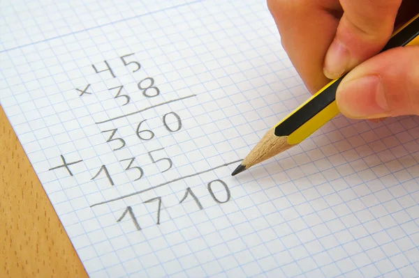 Hand om ett barn att göra en multiplikation med en blyertspenna. Math. Skolan koncept. — Stockfoto