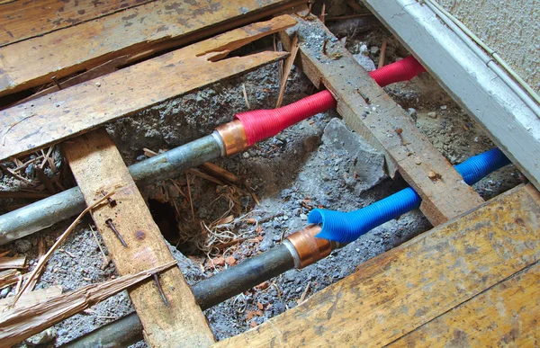 Tuberías de agua fría y caliente bajo suelo de madera roto —  Fotos de Stock