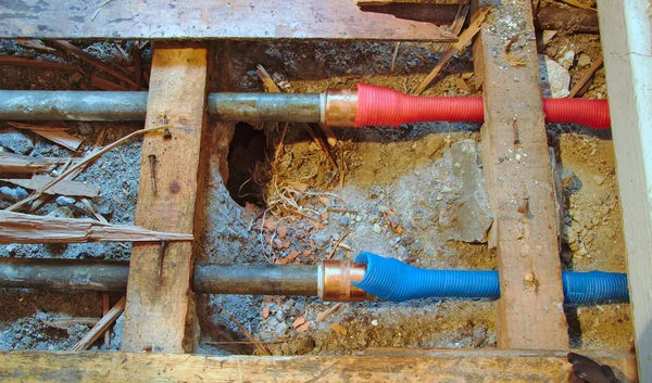 Tuberías de agua fría y caliente bajo suelo de madera roto — Foto de Stock