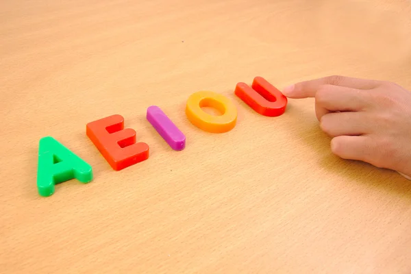 Letters a e i o and u with child hand, school concept