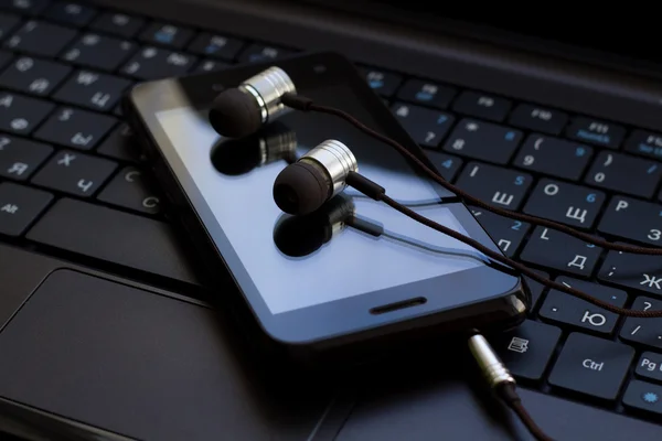 Kopfhörer und Handy an der Tastatur. — Stockfoto