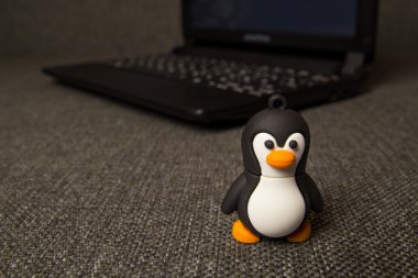 Küçük Tux oyuncak bulanık defter arka plan.