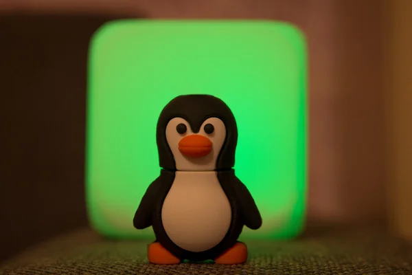 Small Tux Toy at Blurred Green Background. — Stock Photo, Image