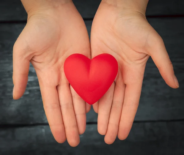 Kırmızı kalp ellerinde.