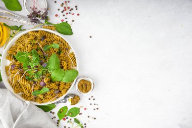 Mikro yeşil ıspanaklı makarna ve gümüş çatal bıçaklı beyaz kasede pesto. Gurme İtalyan yemeği. Üst Manzara. Flatlay. Kopyala lütfen. Sağlıklı beslenme kavramını