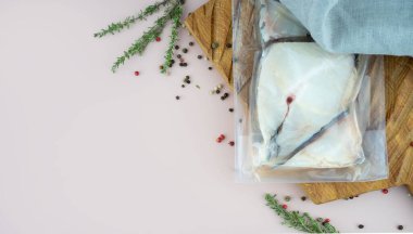 Sous-vide pişirilmiş teknoloji konsepti. Tahta tahtada biberiye ve biberiyeli taze Atlantik pamuk balığı filetosu. Pembe arka planda fotokopi alanı olan üst manzara.