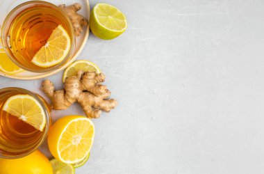 Gri arka planda zencefil, limon ve bal vitaminli sıcak bitki çayı. Alternatif tıp kavramını ele alalım. Soğuk algınlığı ve grip için doğal ev yapımı ilaç. Bağışıklık sistemini destekleyin. Refah ve Sağlık
