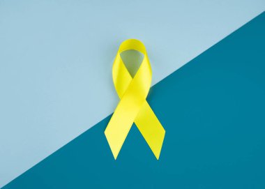Sarı kanser farkındalığı kurdelesi mavi arka planda çocukluk kanseri farkındalığının sembolü. Boşluğu kopyala.