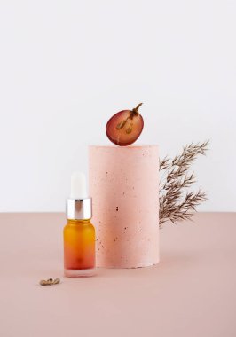 Evde cilt bakımı için cam şişeye üzüm tohumu yağı konsepti. El yapımı alçı taşı podyumu, kaidesi ve kurumuş çiçeklerle yaratıcı yaşam bileşimi. Pembe arka plan. Boşluğu kopyala