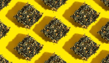 Japanese green tea Genmaicha.Tea leaves with fried brown rice in the shape of a cube on a bright yellow background with a shadow.Pattern.Slimming trend tea concept.Natural product.Self-care and health clipart