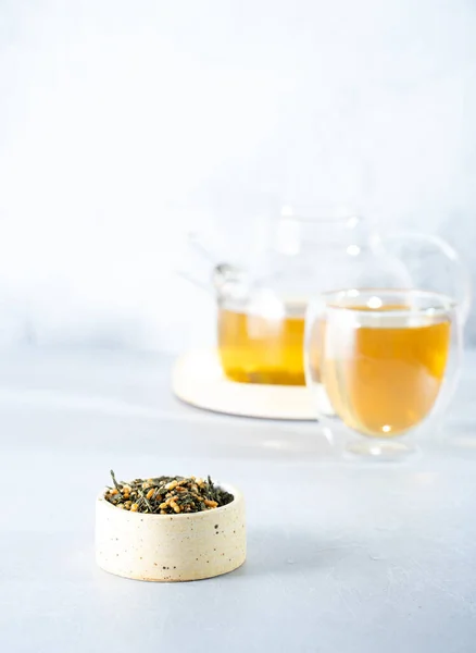 Japanischer grüner Tee Genmaicha.Teeblätter mit gebratenem braunem Reis auf hellgrauem Hintergrund mit einem Schatten. Schlankheitstrend Teekonzept. eine Tasse Tee. Brauen Sie eine transparente Teekanne — Stockfoto