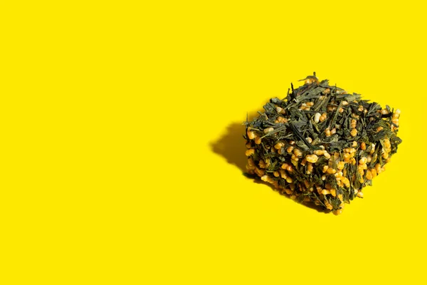 Chá verde japonês Genmaicha. Folhas de chá com arroz integral frito na forma de um cubo em um fundo amarelo brilhante com uma sombra. Conceito de chá tendência de emagrecimento. Produto natural. Autocuidado e saúde — Fotografia de Stock