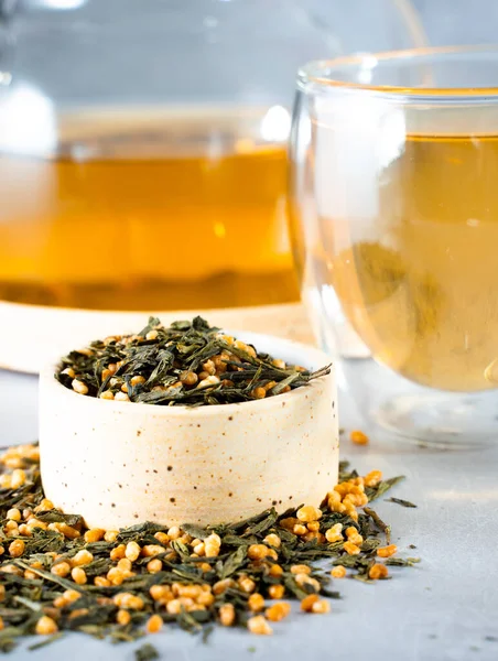 Chá verde japonês Genmaicha.Chá folhas com arroz integral frito em um fundo cinza brilhante com um conceito de chá tendência shadow.Slimming. uma chávena de chá. brew um bule transparente — Fotografia de Stock