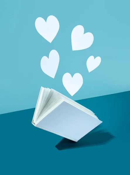Floating Cute paper heart and white cover book on bold color blue-aquamarine-turquoise background. Modern photo. Concept National Book Lovers Day. happy holydays.Romantic, love storytelling.copy space