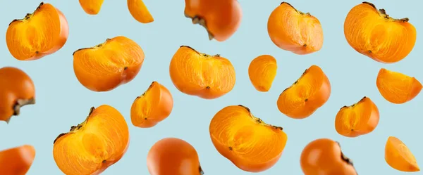 Frutta fresca arancione galleggiante variopinta intera e affettata di cachi biologici con foglie su fondo blu. Note di alimentazione e concetto di cibo. Levitazioni cibo. Layout creativo per elemento Design — Foto Stock