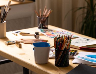 Yağlı boya tüpleri ve renkli kalemlerle boya fırçası. Sanat aletleri, mürekkep, ahşap tablo. Çağdaş sanatçılar için resim. Yetişkinler için yaratıcı eşyalar. Suluboya çizimleri.