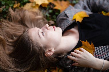 Kız sonbahar yaprağı, sonbahar zamanı. Yapraklar kıyafetlerin üzerinde yatıyor..