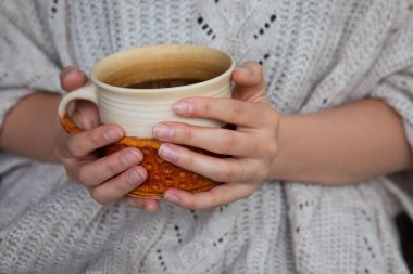 Elinde çay fincanı tutan genç bir kadın. Sonbahar ya da kış karamsar hafta sonu. Tembel gün, karantina, evde kal, rahat sahne, kızlık zarı konsepti.