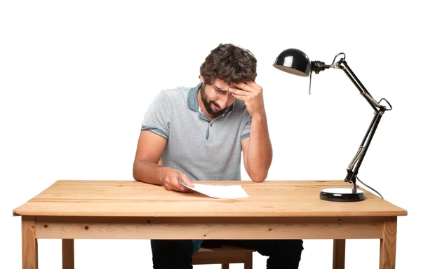 Crazy young man at table with paper — Stock Photo, Image